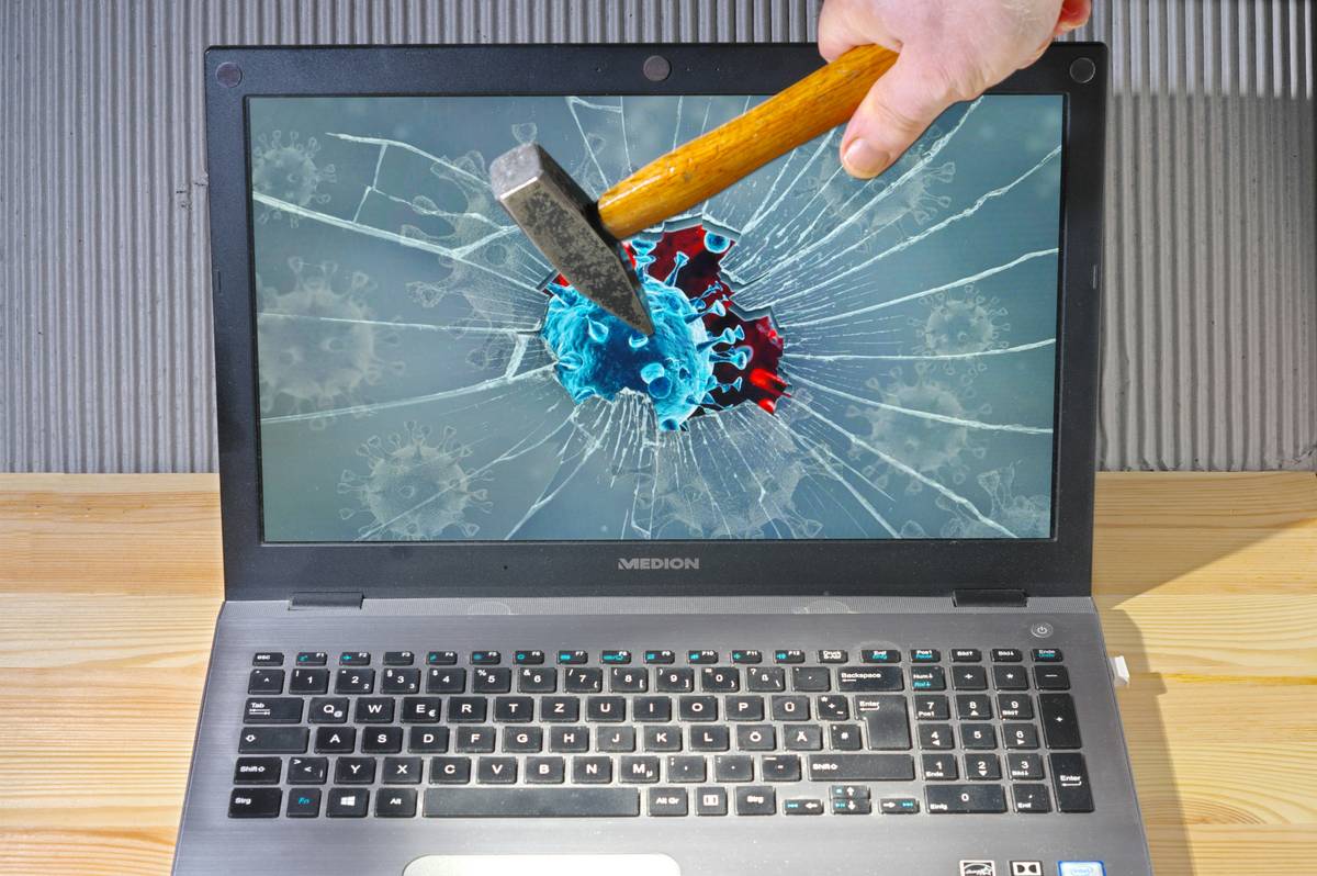 Traveler inspecting cracked laptop screen with Electronics Damage Coverage documents nearby